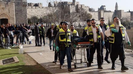 Helfer bringen die Leiche eines der beiden palästinensischen Angreifers fort.