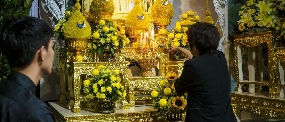 nTrauer, Gedenken und Erinnerung - eine Frau entzündet in einem buddhistischen Tempel in Bangkok eine Kerze für den verstorbenen König.