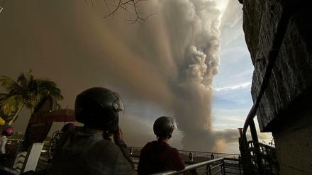 Menschen beobachten auf einer Brücke riesige Rauchwolken.
