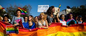 Menschen marschieren mit Regenbogenfahnen und Schildern während der jährlichen Gay-Pride-Parade in Jerusalem.