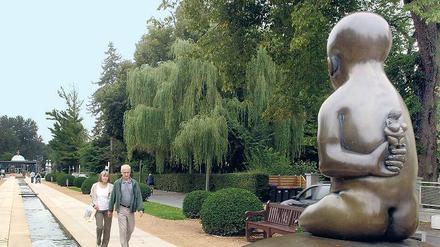 Versteckt. Skulpturen von Jürgen Goertz sind am Kurpark von Bad Pyrmont aufgestellt. Das Kind auf der Weltkugel hält - so Lästermäuler - den Kurschatten hinter seinem Rücken.