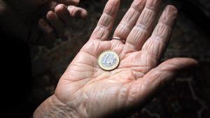 Eine 83-jährige Frau hält eine Euromünze in der geöffneten Handfläche.