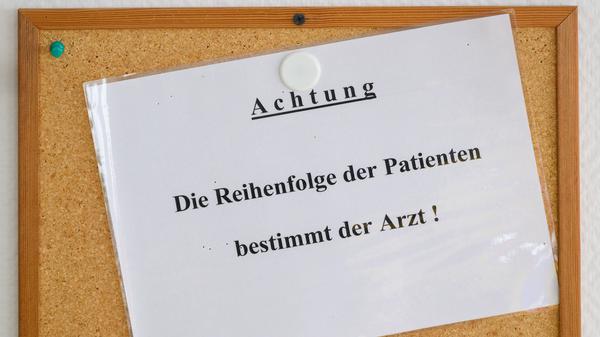 Ein Schild „Achtung. Die Reihenfolge der Patienten bestimmt der Arzt!“ hängt in einer Kinderarztpraxis im Wartezimmer.