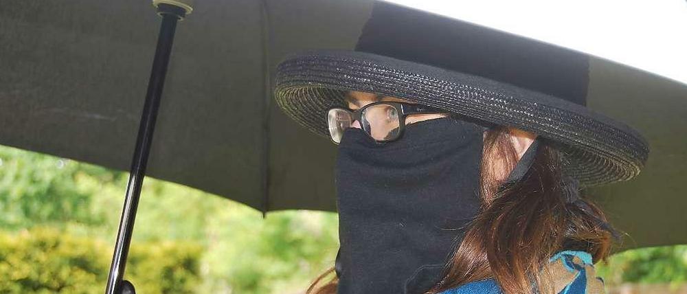 Anna Meier muss sich mit Schirm und Gesichtsschleier schützen. 