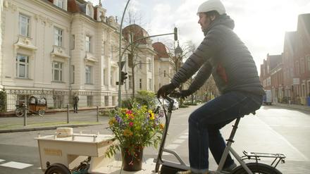 Mit dem Lastenfahrrad zum Friedhof. Eric Wrede transportiert Blumen geschmückte Urnen auch per Rad und die Hinterbliebenen radeln hinterher.