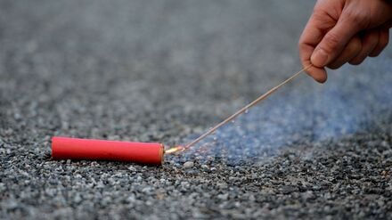 Der Bildausschnitt zeigt eine Hand, die einen Böller anzündet.