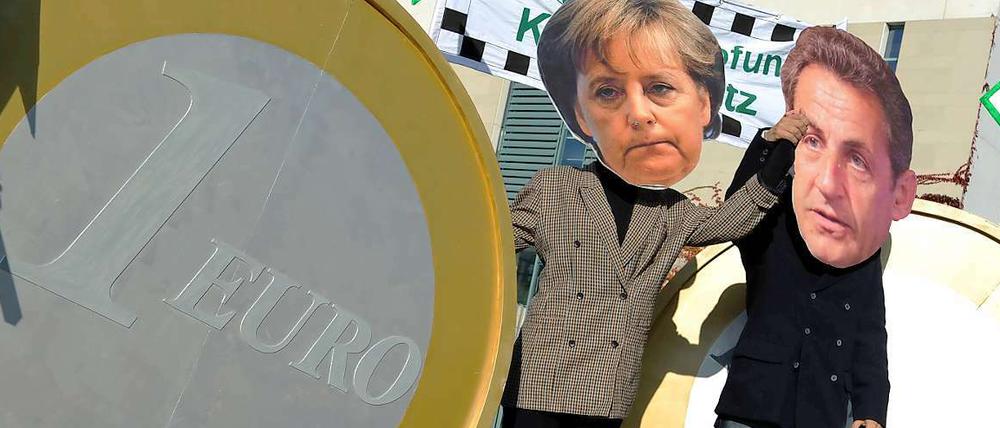 Zerrbilder aus Pappmaché: Im Oktober 2011 stehen Demonstranten mit Merkel- und Sarkozy-Masken vor dem Berliner Kanzleramt.