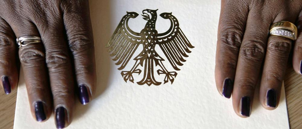 Die Hände einer Neubürgerin liegen im Rathaus Berlin-Neukölln während einer Feierstunde auf einer Einbürgerungsurkunde der Bundesrepublik Deutschland.