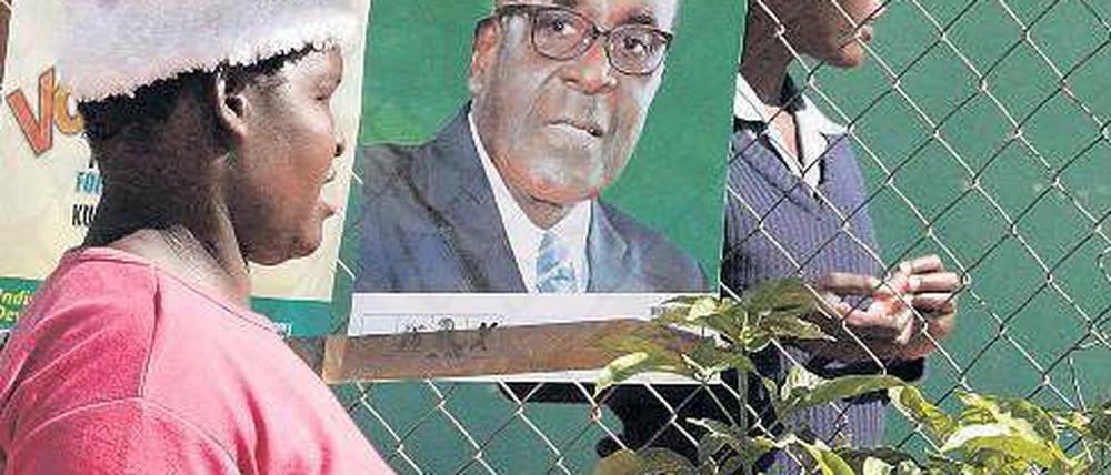 Ruhe vor dem Wahltag: In Simbabwes Hauptstadt Harare hängen Plakate von Staatschef Mugabe und seinem Herausforderer Tsvangirai (rechts). Foto: Philimon Bulawayo/Reuters
