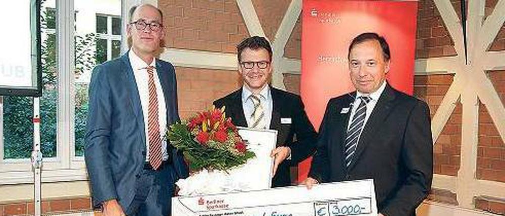 Stolz mit Scheck: FU-Präsident Peter-André Alt (l.) und Michael Jänichen, Leiter Firmenkundengeschäft der Berliner Sparkasse, freuen sich mit Jan Baars (r.).