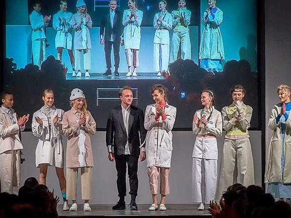 Ein junger Modedesigner wird von seinen Models beklatscht