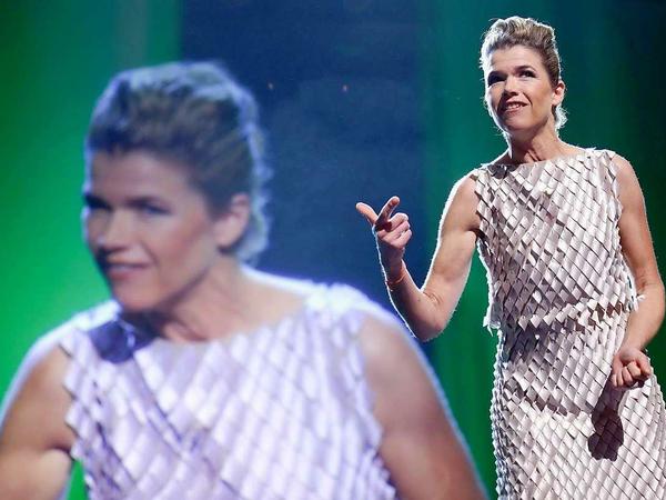 Anke Engelke moderiert in einem Kleid, das keine Ärmel hat und aussieht wie silberne Schuppen