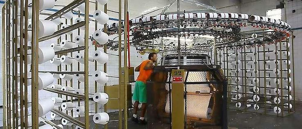 Mensch und Maschine. Filmstill aus einer Fabrik in Rio de Janeiro.