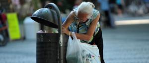 Eine ältere Frau sucht in einem Müllbehälter in Weimar nach Pfandflaschen.