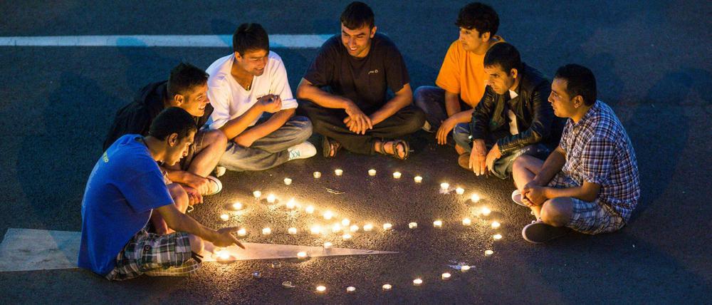 Flüchtlinge sitzen am Abend des 24.08.2015 vor dem ehemaligen Praktiker-Baumarkt in Heidenau vor einem Peace-Zeichen, das sie aus Teelichtern geformt haben.