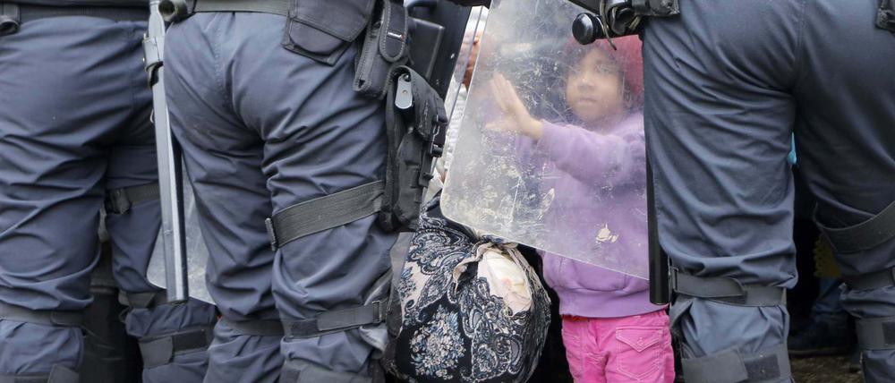 Etappe auf der Flucht. Ein kleines Mädchen berührt im slowenischen Grenzort Rigonce den Schutzschild eines Polizisten.