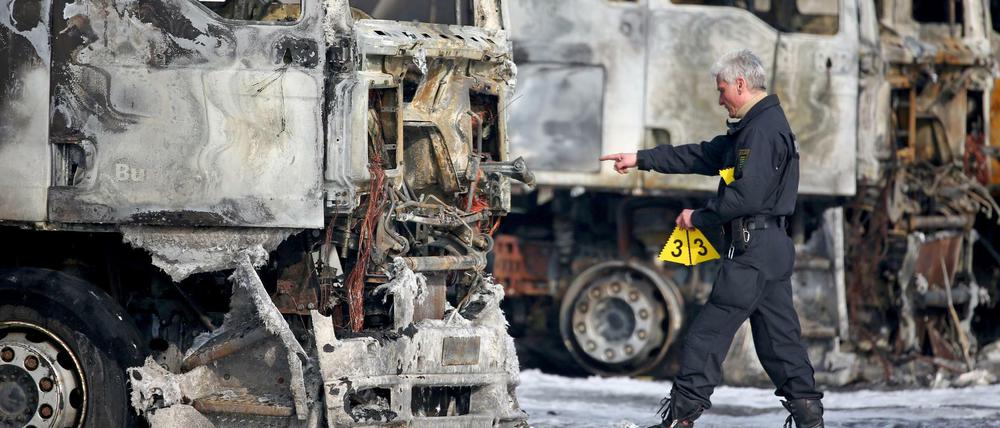 Ein Polizist sichert Spuren an mehreren ausgebrannten Lkw der Bundeswehr am Dienstag in Leipzig. Unbekannte Brandstifter haben auf dem Werkstattgelände acht Lastwagen und zwei Anhänger angezündet - sechs dieser Fahrzeuge gehören der Bundeswehr.