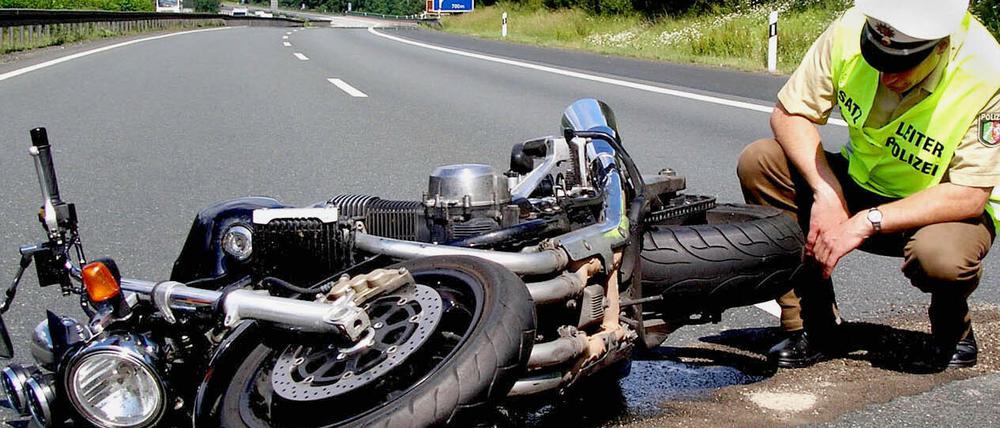 Ein Polizist begutachtet ein verunfalltes Motorrad.