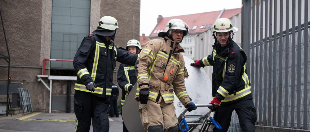 Feuerwehrleute transportieren den Gefahrgutbehälter mit der explodierten Batterie von der Volksbühne ab.