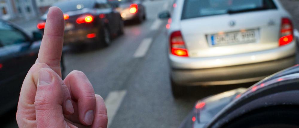 Autofahrer zeigt "Stinkefinger" aus seinem Auto.