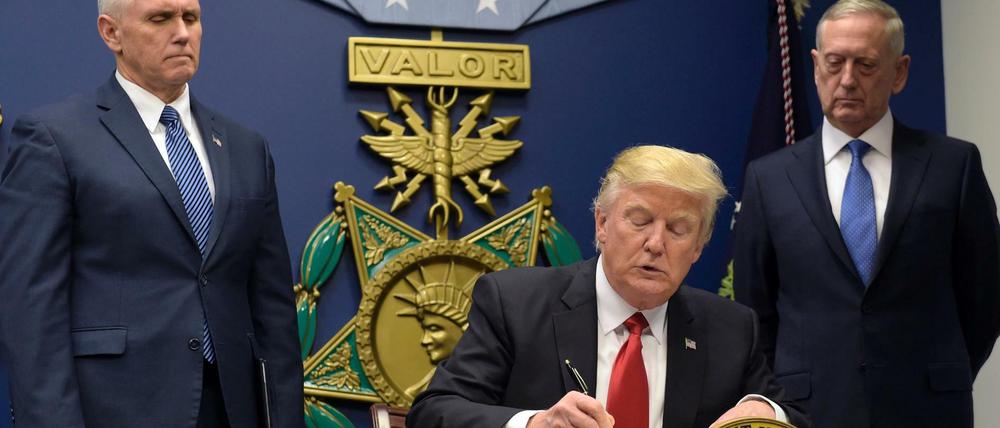 Mit Signatur und Siegel. Donald Trump unterschreibt neben Verteidigungsminister James Mattis (r) und Vizepräsident Mike Pence (l) im Pentagon sein Exekutiv-Dekret, mit dem der Zustrom von Flüchtlingen verringert werden soll.