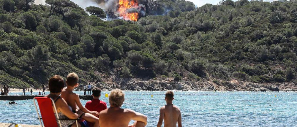 Urlauber an einem Strand nahe Saint-Tropez beobachten die Waldbrände.