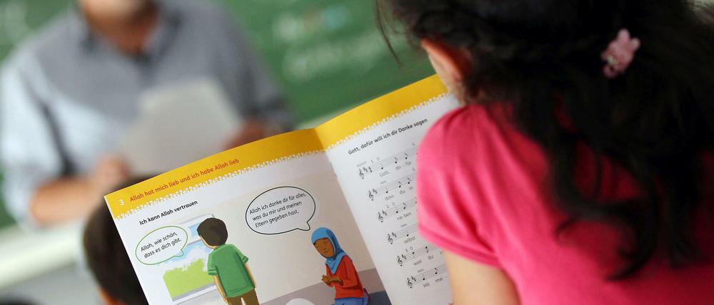 Ein Mädchen liest an einer Bonner Schule während des islamischen Religionsunterrichts in einem Schulbuch.