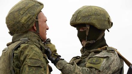 Ein russischer Ausbilder kleidet einen russischen Rekruten während einer militärischen Trainingseinheit korrekt an.