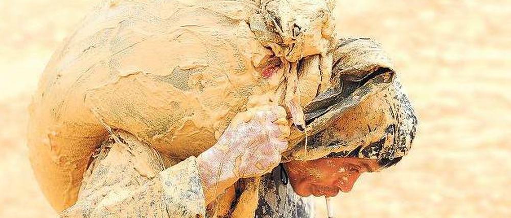 Der Reichtum dieser Welt. Wertvolle Erde trägt dieser chinesische Arbeiter in der Provinz Jiangxi auf seiner Schulter.