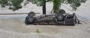 Ein fortgespültes Auto liegt nach einer Sturzflut in Indien unter einem Baum.