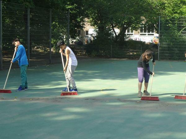 Schüler fegen das Schulgelände