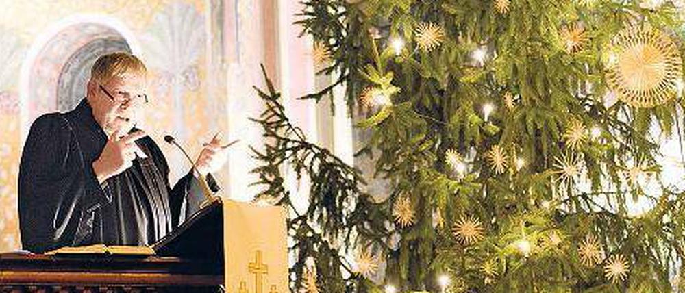 Ein Pfarrer pregigt. Neben ihm steht ein Christbaum.