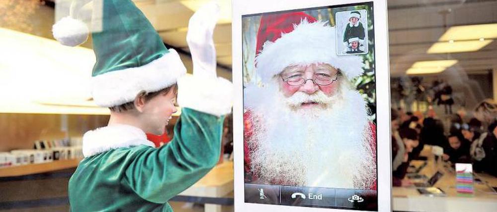 Weihnachtself grüßt Weihnachtsmann. In diesem Apple-Store machen beide Werbung für das iPhone.
