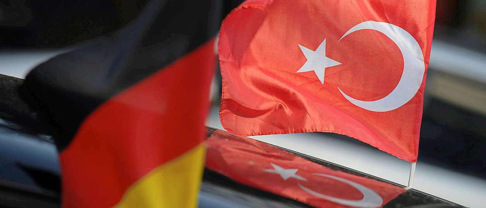 Eine deutsche und eine türkische Fahne wehen in Berlin während der Fußball-Europameisterschaft an einem Auto.