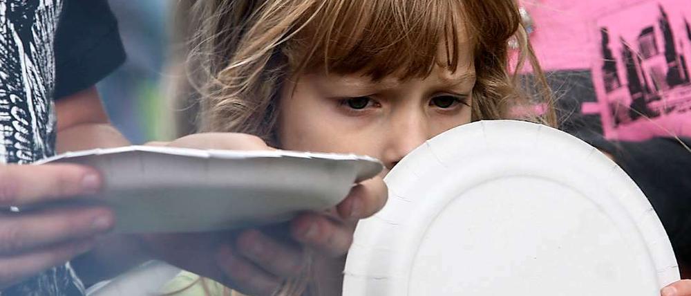 Sommerfest beim Kinderhilfswerk Arche: Ein Mädchen wartet auf ein Grillwürstchen. In Berlin ist fast jedes zweite Kind arm.