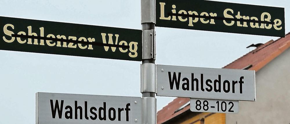 Die alten Straßennamen in Wahlsdorf (Brandenburg) sind durchgestrichen. Nach der Gemeindereform wurden neue Schilder angebracht, die den Weg zu den durchnummerierten Häusern weisen.