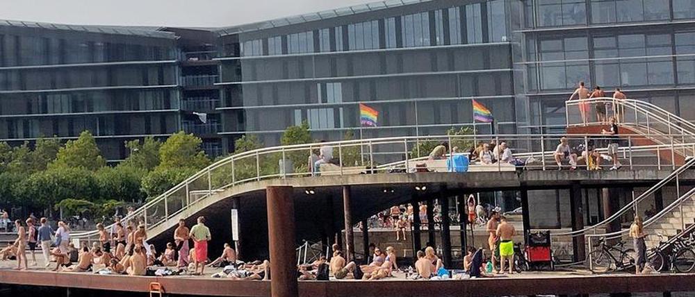 Menschen freuen sich im Zentrum Kopenhagens über das sonnige Wetter. Leitern ermöglichen ihnen einen komfortablen Zugang zum Wasser. 