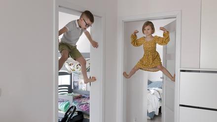 Zwei Kinder klettern den Türrahmen hoch. 