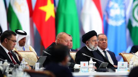 Der iranische Prräsident Ebrahim Raisi sitzt dem russischen Außenminister Sergei Lavrov während einer Konferenz gegenüber. 