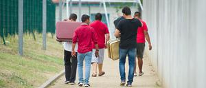 Flüchtlinge laufen mit Koffern bepackt auf einem Weg einer Erstaufnahmeeinrichtung für Flüchtlinge in Ingelheim (Rheinland-Pfalz) entlang. 