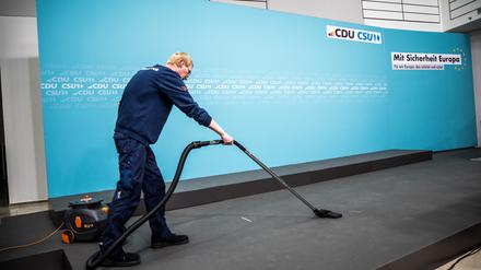 Wer wenig verdient, kann aufstocken. Hier will die CDU Neuerungen. Ein Gebäudereiniger saugt das Podium vor einer gemeinsamen Pressekonferenz von CDU und CSU.