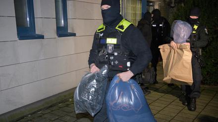 Durchsuchungen in Berlin: Polizisten tragen sichergestellte Beweismittel aus einem Haus.