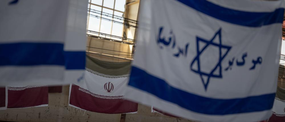 Iranische Flaggen und israelische mit der Aufschrift „Tod Israels“ hängen zum Trocknen in einer Fabrikhalle. 