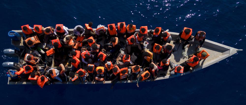 Migranten aus Eritrea, Libyen und dem Sudan sitzen in einem Holzboot.