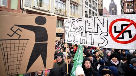 Demonstranten halten während einer Demonstration gegen Rassismus und rechtsextreme Politik in Frankfurt am Main am 20. Januar 2024 Plakate mit einem weggeworfenen und einem durchgestrichenen Hakenkreuz in der Hand.