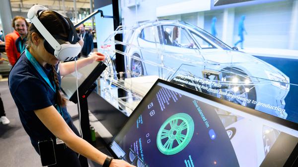 Eine Siemens-Mitarbeiterin steht mit einer AR-Brille (Augmented-Reality) auf der Hannover Messe und zeigt eine Simulation aus der Automobilindustrie.