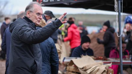 Rainer Haseloff (CDU), Ministerpräsident von Sachsen-Anhalt, reagiert auf einen Pöbler bei der zentralen Sandsackbefüllungsanlage. 