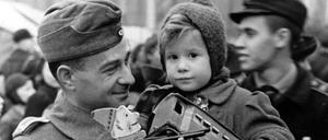 Unsere Mütter, unsere Väter. Ein Fronturlauber der Deutschen Wehrmacht trägt sein Kind über den Weihnachtsmarkt - im Berliner Lustgarten im Winter 1942. 