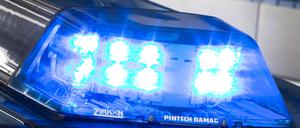 Eine Blaulicht leuchtet auf dem Dach eines Polizeiwagens. Im Hintergrund steht ein weiterer Streifenwagen. (Symbolbild)