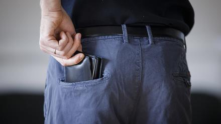  Symbolfoto. Ein Mann zieht eine Geldbörse aus seiner Hosentasche.